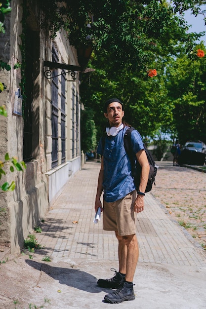 Jeune homme latin regardant le ciel sur le trottoir d'une ville coloniale avec une rue pavée Photo verticale