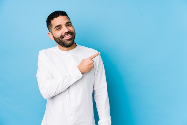 Jeune homme latin souriant et pointant de côté, montrant quelque chose