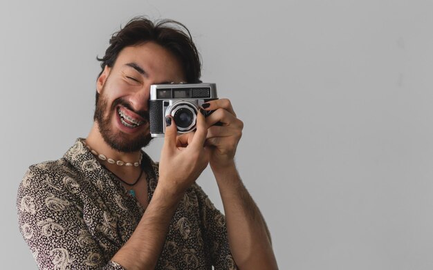Jeune homme latin souriant prenant des photos avec des ongles peints sur fond blanc Espace de copie