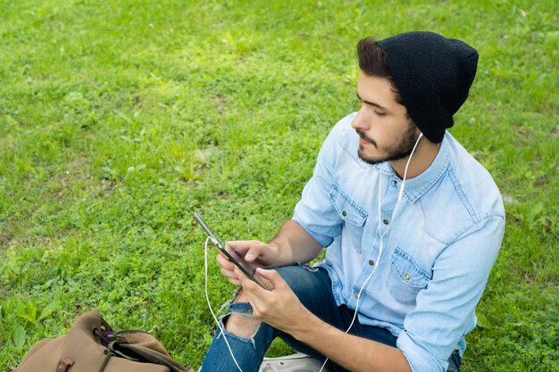 Jeune homme latin avec tablette à l&#39;extérieur.