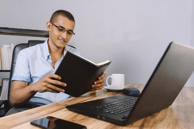 Photo un jeune homme latino-américain lisant un livre, un étudiant hispanique révisant ses annotations sur son bureau.