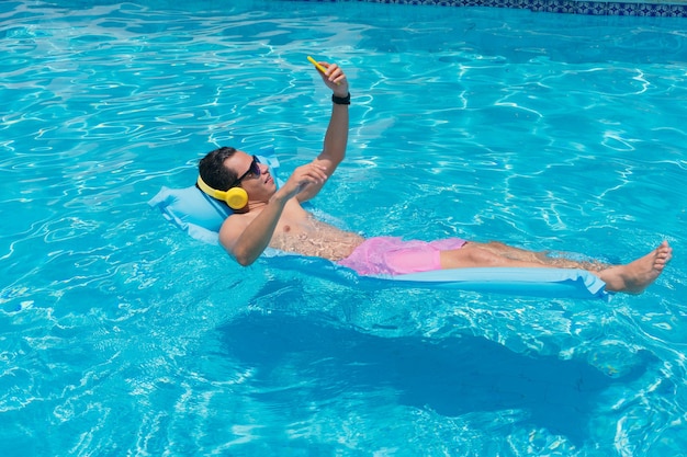 Jeune homme latino à la piscine à l'aide de son téléphone portable.