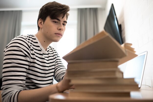 Jeune homme, lecture, pile livres, chez soi