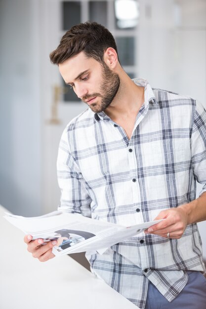 Jeune homme lisant des documents à table dans la maison