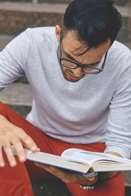 Jeune homme lisant un livre sur le campus