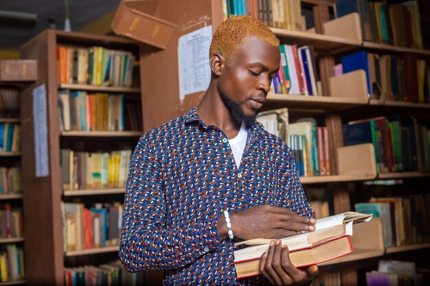 Jeune homme lisant un livre dans la bibliothèque