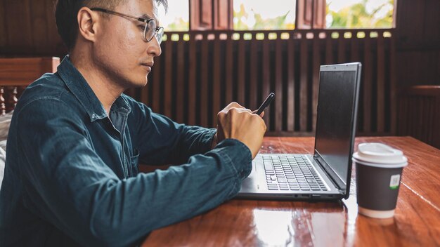 Jeune homme avec des lunettes à l'aide d'un ordinateur portable en tapant sur un clavier en écrivant des e-mails ou en travaillant en ligne