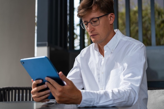 Jeune homme à lunettes à l'aide d'une tablette au bureau