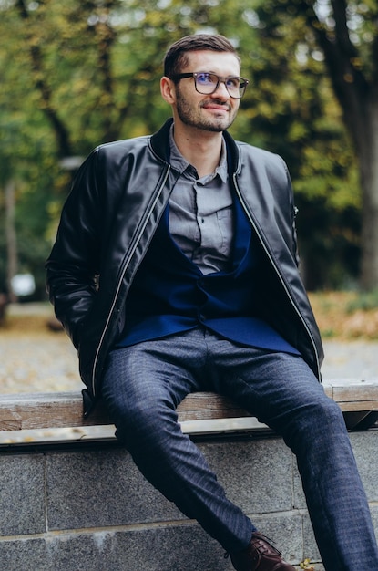 un jeune homme à lunettes est assis sur un banc