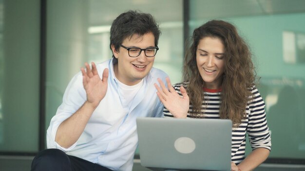 Jeune homme à lunettes et femme avec ordinateur portable faisant un appel vidéo vêtements décontractés