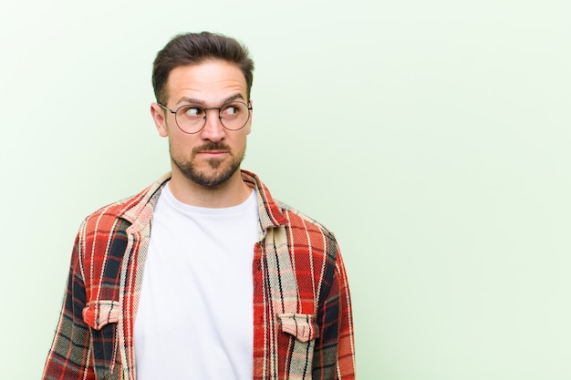 un jeune homme avec des lunettes posant tout en se demandant