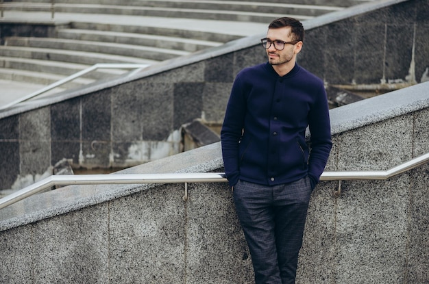 un jeune homme à lunettes près de la balustrade