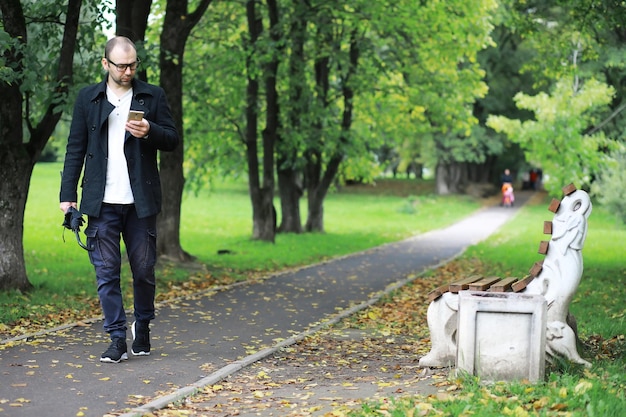 Photo un jeune homme à lunettes se promène dans le parc avec un parapluie pendant la pluie.