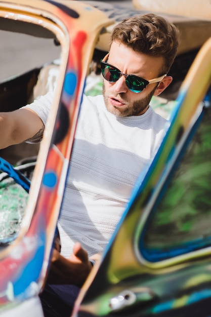 jeune homme à lunettes de soleil dans un cabriolet