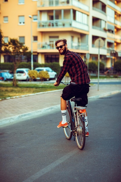 Jeune homme à lunettes de soleil faisant du vélo dans la rue de la ville