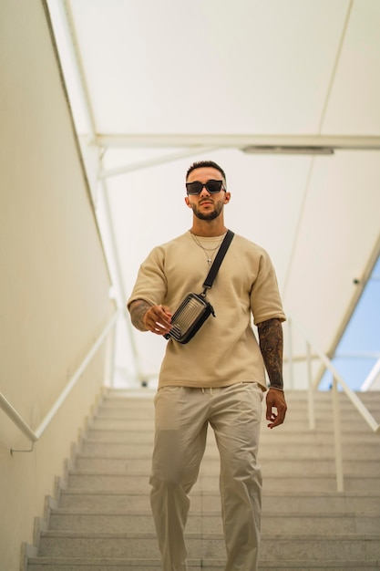 Jeune homme avec des lunettes de soleil portant des vêtements blancs debout dans un bâtiment