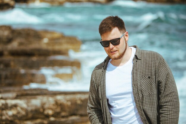 Jeune homme à lunettes de soleil avec portrait de barbe en vacances d'été en bord de mer