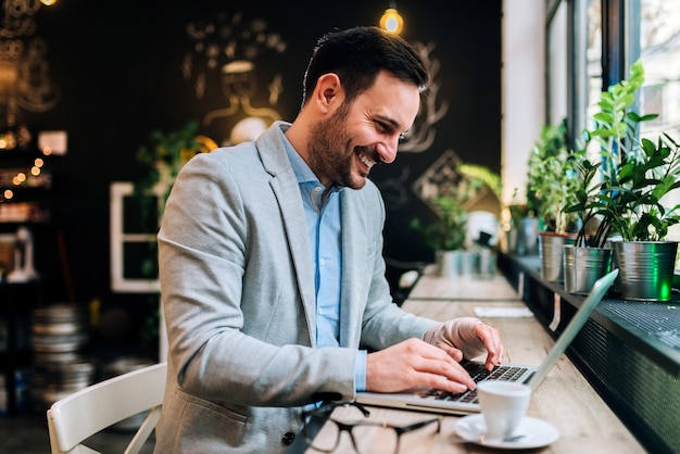 Jeune homme avec une main bandée assis devant un ordinateur portable au café.