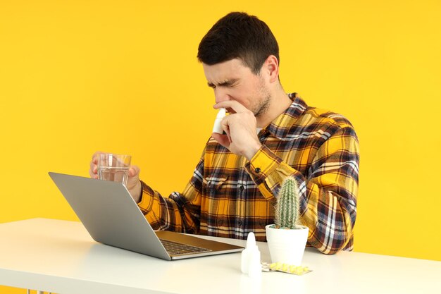 Jeune homme malade s'asseyant sur le lieu de travail, concept froid saisonnier