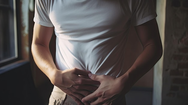 Photo un jeune homme malheureux et bouleversé tenant son abdomen avec les deux mains souffrant de maux de ventre isolé sur fond gris