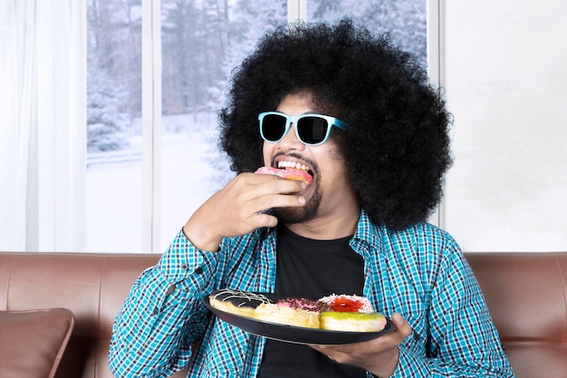 Photo le jeune homme mange des beignets sucrés.