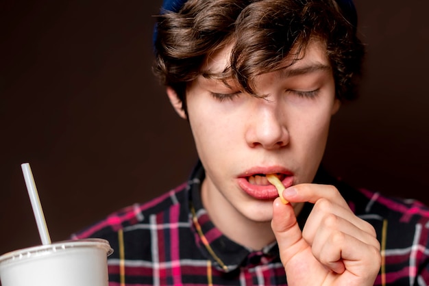 Un jeune homme mange des pommes de terre frites sans soda bb