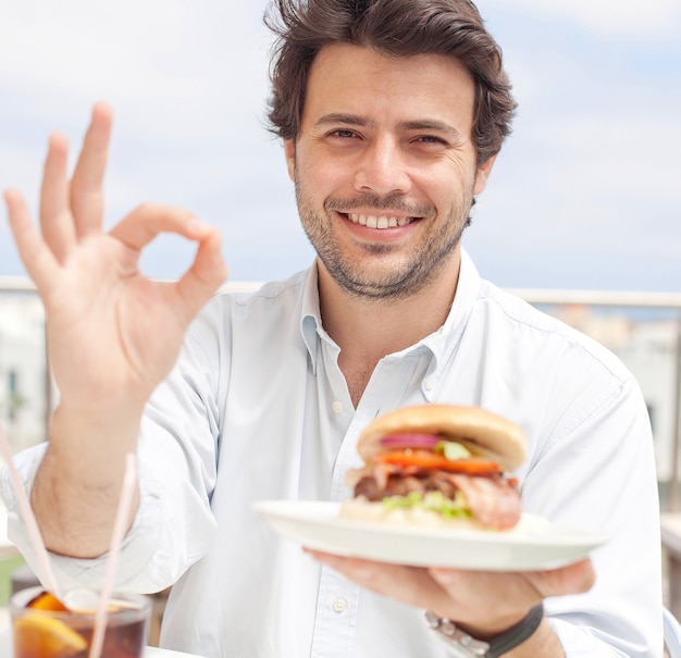 Jeune homme mangeant un hamburguer