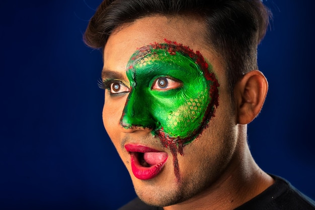 Un jeune homme avec un maquillage créatif d'art sur son visage comme un portrait de demi-visage de serpent avec un maquillage de zombie effrayant ou un art du visage d'Halloween