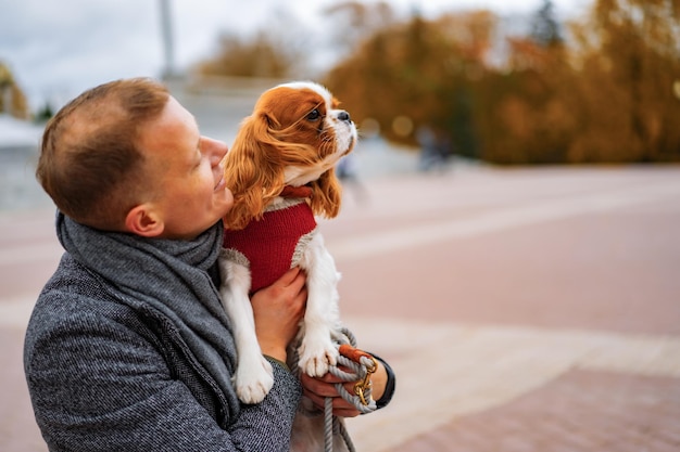 Jeune homme marchant avec un chien dans le parc en automne