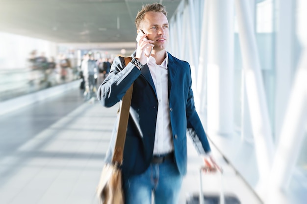 Jeune homme marchant dans l'aéroport et parlant au téléphone