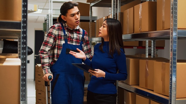 Jeune homme marchant dans des béquilles avec une femme propriétaire, parlant de la gestion des stocks et de l'inventaire. Entrepreneur travaillant avec une tablette pour analyser la marchandise, travail d'équipe avec un employé.