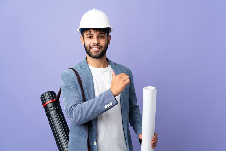 Photo jeune homme marocain architecte avec casque et tenant des plans isolés
