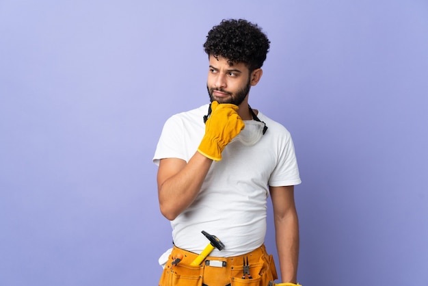 Jeune homme marocain électricien isolé sur mur violet et levant