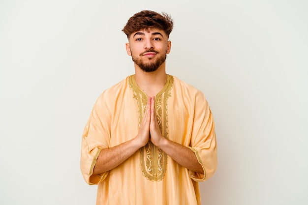 Jeune homme marocain isolé sur blanc priant, montrant la dévotion, personne religieuse à la recherche d'inspiration divine.