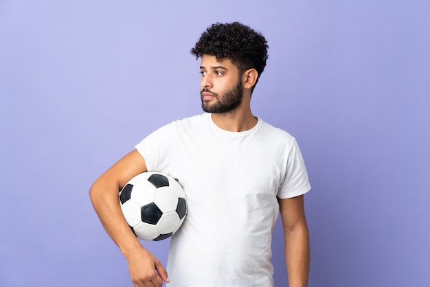 Jeune homme marocain isolé sur fond violet avec ballon de foot