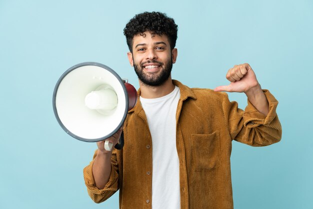 Jeune homme marocain isolé tenant un mégaphone et fier et satisfait de soi