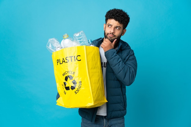 Jeune homme marocain tenant un sac plein de bouteilles en plastique à recycler isolé