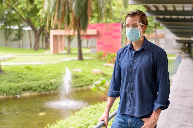 Jeune homme avec masque et écran facial pour se protéger de l'épidémie de coronavirus dans le parc