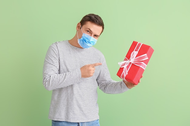 Jeune homme en masque médical et avec cadeau en couleur