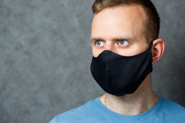 Jeune homme en masque médical de protection noir contre les virus. COVID 19