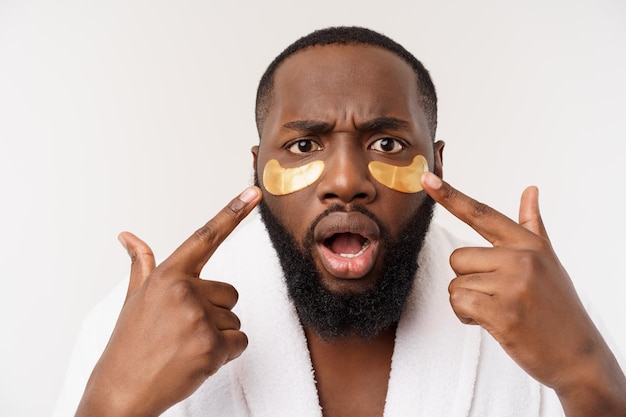 Un jeune homme avec un masque pour les yeux en papier sur le visage qui a l'air choqué avec une bouche ouverte isolée sur un dos blanc