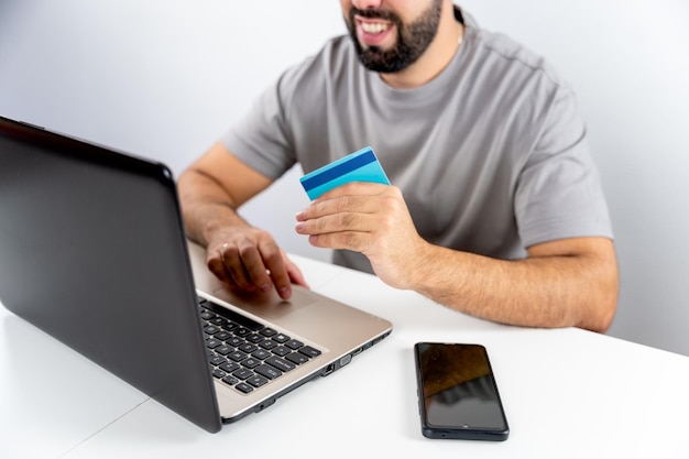 Jeune homme méconnaissable avec ordinateur et carte de maintien pour faire des achats en ligne à domicile concept shopping vendredi noir cyber lundi ventes noël