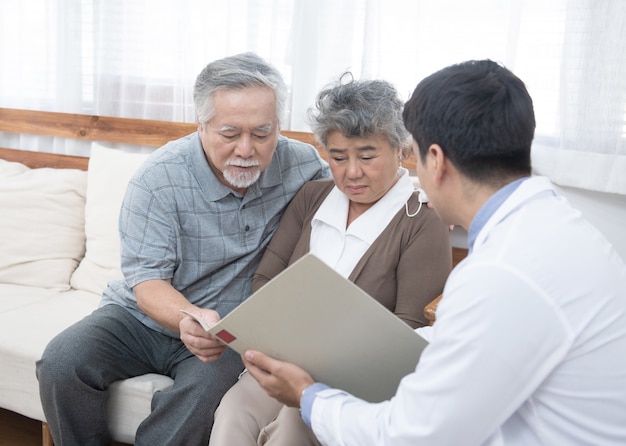 Jeune homme médecin caucasien parler du résultat de l'examen sur la tablette pour les personnes âgées âgées âgées retraite asiatique femme avec vieil homme prendre soin d'elle à côté de soins de santé et concept médical.