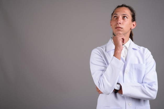 Jeune homme médecin avec des dreadlocks sur fond gris