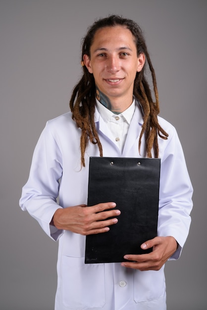 Jeune homme médecin avec des dreadlocks sur fond gris