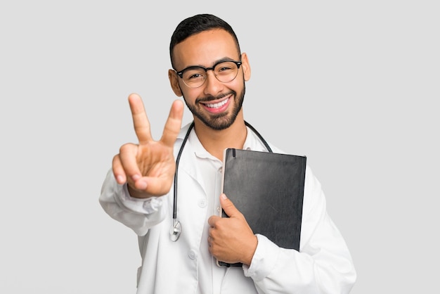 Jeune homme médecin latin tenant un livre isolé