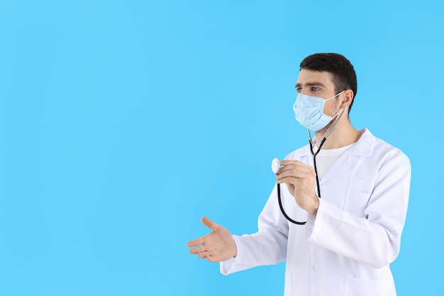 Jeune homme médecin avec stéthoscope sur fond bleu