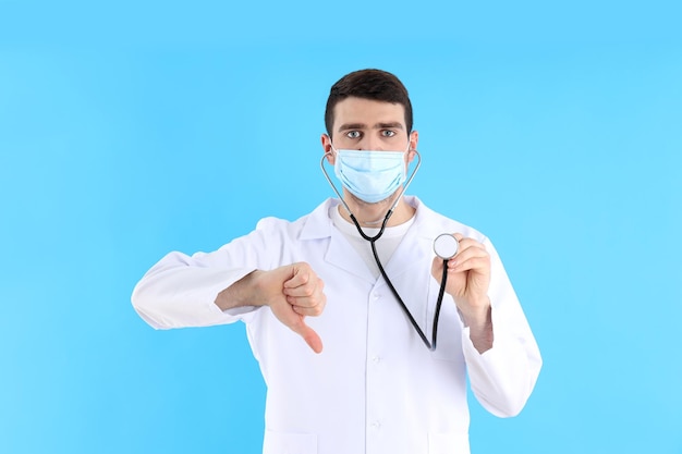 Jeune homme médecin avec stéthoscope sur fond bleu