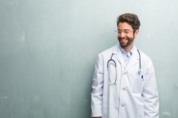 Jeune homme médecin sympathique contre un mur de grunge avec un espace de copie rire et s&#39;amuser