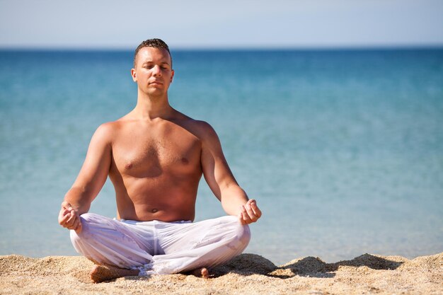 Jeune homme méditant sur la plage